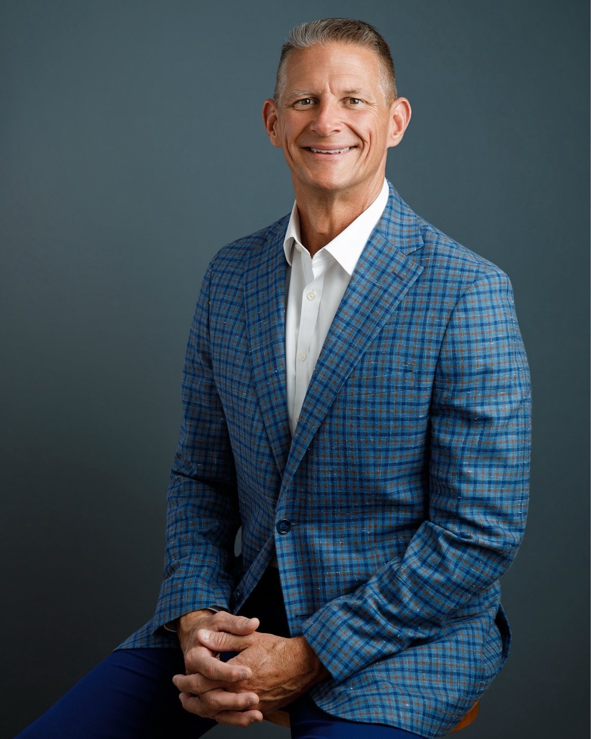 Portrait of Jason Hurta, smiling, in a blue plaid sport coat