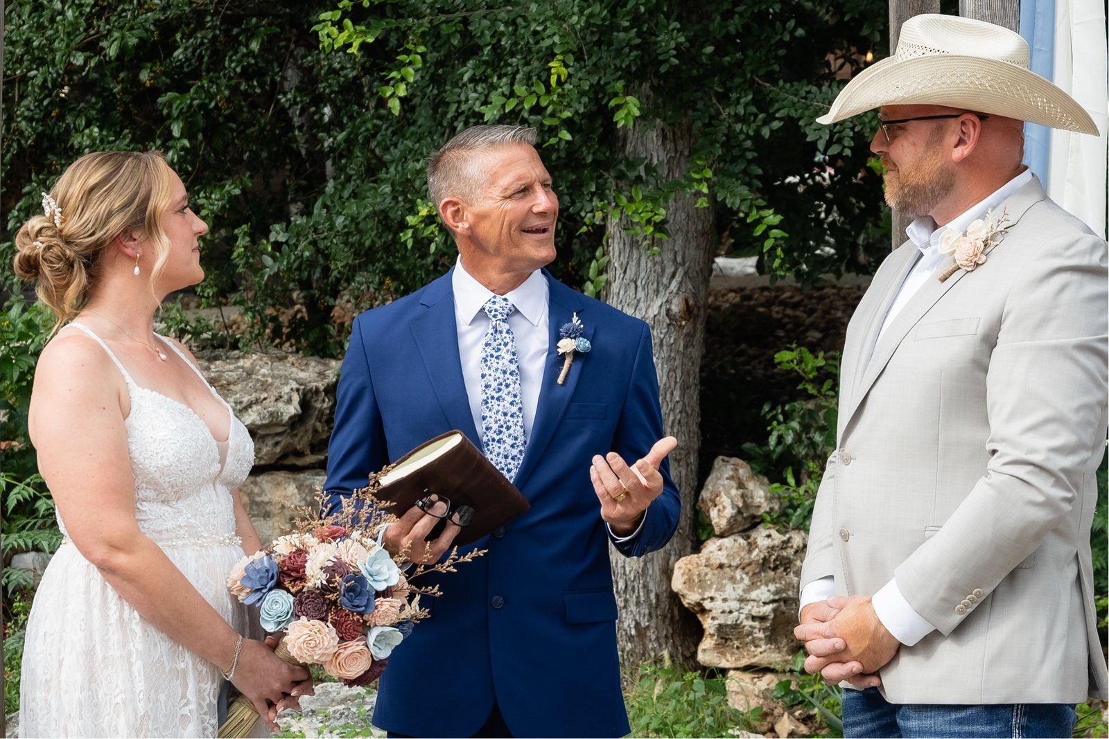 Jason Hurta officiating an outdoor Hill Country wedding ceremony, speaking with the bride and groom